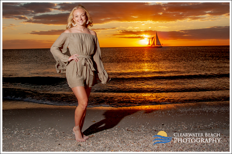 Sunset Senior Portrait of Girl standing on Clearwater Beach with sailboat 